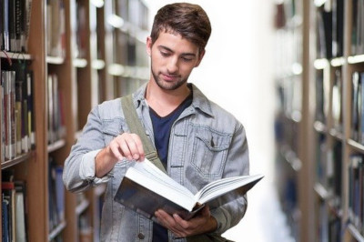 Image d'une personne étudiant un livre dans une bibliothèque
